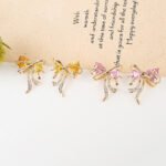 Wholesale Pink Ribbon Earrings with trillion-cut pink crystals and 925 silver needles on gold plated brass from JuneJewelry.com.