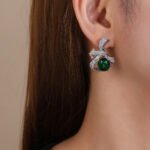Wholesale red ribbon earrings with green zircons and 925 silver needles from JuneJewelry.com – unique bow-knot fashion jewelry for bulk buyers.