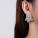 Wholesale zircon flower earrings with white pavé petals on real gold plated copper from JuneJewelry.com – luxury floral studs for bulk orders.