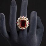 Wholesale emerald cut ring with a large red zircon and 18K gold plated copper band from JuneJewelry.com – adjustable luxury jewelry for bulk orders.