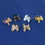 Wholesale butterfly open ring with pink zircon stones and real gold plating on copper from JuneJewelry.com – adjustable fashion ring for bulk orders.