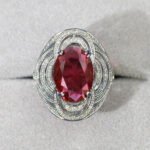 Wholesale blue zircon ring with oval-cut center stone and tiered halo design on gold plated copper from JuneJewelry.com – adjustable cocktail jewelry for bulk orders.