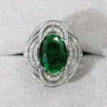 Wholesale blue zircon ring with oval-cut center stone and tiered halo design on gold plated copper from JuneJewelry.com – adjustable cocktail jewelry for bulk orders.