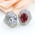 Wholesale blue zircon ring with oval-cut center stone and tiered halo design on gold plated copper from JuneJewelry.com – adjustable cocktail jewelry for bulk orders.