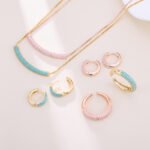 Niche light luxury geometric turquoise jewelry set wholesale displaying a micro-pave turquoise-blue curved bar smile necklace, matching huggie hoop earrings, and an open adjustable ring on junejewelry.com