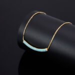 Niche light luxury geometric turquoise jewelry set wholesale displaying a micro-pave turquoise-blue curved bar smile necklace, matching huggie hoop earrings, and an open adjustable ring on junejewelry.com