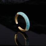 Niche light luxury geometric turquoise jewelry set wholesale displaying a micro-pave turquoise-blue curved bar smile necklace, matching huggie hoop earrings, and an open adjustable ring on junejewelry.com