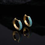 Niche light luxury geometric turquoise jewelry set wholesale displaying a micro-pave turquoise-blue curved bar smile necklace, matching huggie hoop earrings, and an open adjustable ring on junejewelry.com