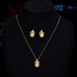 High-end light luxury crown pearl jewelry set wholesale featuring a delicate micro-pave zircon tiara cap pendant necklace and matching pearl stud earrings on junejewelry.com