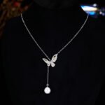 Niche light luxury butterfly zircon jewelry set wholesale featuring an intricate micro-pave crystal butterfly Y-shaped choker necklace with a drop pearl and matching butterfly stud earrings on junejewelry.com