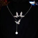 Niche light luxury butterfly zircon jewelry set wholesale featuring an intricate micro-pave crystal butterfly Y-shaped choker necklace with a drop pearl and matching butterfly stud earrings on junejewelry.com