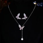 Niche light luxury butterfly zircon jewelry set wholesale featuring an intricate micro-pave crystal butterfly Y-shaped choker necklace with a drop pearl and matching butterfly stud earrings on junejewelry.com