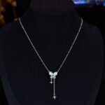 Niche summer blue crystal butterfly jewelry set wholesale featuring an aquamarine pear-cut gemstone butterfly pendant with dangling star chain tassels and matching butterfly stud earrings from junejewelry.com