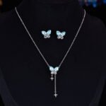 Niche summer blue crystal butterfly jewelry set wholesale featuring an aquamarine pear-cut gemstone butterfly pendant with dangling star chain tassels and matching butterfly stud earrings from junejewelry.com
