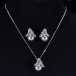 Elegant floral pearl jewelry set wholesale featuring a delicate micro-pave zircon botanical leaf crown capping a large, high-luster round pearl on a pendant necklace and matching stud earrings from junejewelry.com.