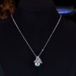 Elegant floral pearl jewelry set wholesale featuring a delicate micro-pave zircon botanical leaf crown capping a large, high-luster round pearl on a pendant necklace and matching stud earrings from junejewelry.com.