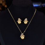 Elegant floral pearl jewelry set wholesale featuring a delicate micro-pave zircon botanical leaf crown capping a large, high-luster round pearl on a pendant necklace and matching stud earrings from junejewelry.com.