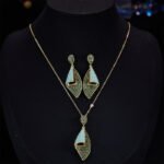 Western heavy-craft geometric conch shell zircon jewelry set wholesale featuring a curved, bi-color micro-pave emerald green and turquoise blue fold pendant necklace and matching drop earrings from junejewelry.com