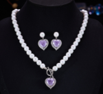 Light luxury ice-cracked zircon heart pearl jewelry set wholesale featuring a classic round pearl strand necklace with a front-facing OT toggle clasp, a micro-pave halo peach heart pendant, and matching pearl-topped drop earrings from junejewelry.com