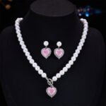 Light luxury ice-cracked zircon heart pearl jewelry set wholesale featuring a classic round pearl strand necklace with a front-facing OT toggle clasp, a micro-pave halo peach heart pendant, and matching pearl-topped drop earrings from junejewelry.com
