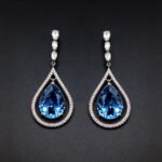Wholesale waterdrop crystal earrings with blue Swarovski Element crystals in platinum plated brass from JuneJewelry.com – luxury dangle earrings for bulk orders.
