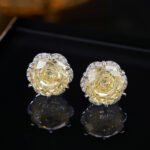 Rose-cut CZ floral stud earrings featuring round rose-faceted center stones framed in micro-pavé CZ scalloped borders, available in soft pink and champagne yellow.