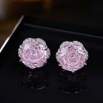 Rose-cut CZ floral stud earrings featuring round rose-faceted center stones framed in micro-pavé CZ scalloped borders, available in soft pink and champagne yellow.