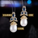 Tear-shaped pearl drop earrings featuring three teardrop crystal clusters top and micro-pavé cap accents, available in gold and palladium plating.