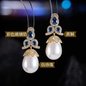 Tear-shaped pearl drop earrings featuring three teardrop crystal clusters top and micro-pavé cap accents, available in gold and palladium plating.