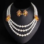 Wholesale Emerald Pearl Set featuring multi strand white shell pearls with green CZ leaf clasps on gold plated copper from JuneJewelry.com.