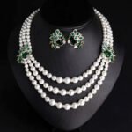 Wholesale Emerald Pearl Set featuring multi strand white shell pearls with green CZ leaf clasps on gold plated copper from JuneJewelry.com.