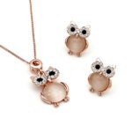 Wholesale crystal owl jewelry set in rose gold plated zinc alloy featuring round cabochon cat eye stone body and pave crystal halo eyes pendant necklace and stud earrings from JuneJewelry.com.