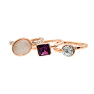 Wholesale stackable stone ring set in rose gold plated zinc alloy featuring an oval cat eye stone ring, square purple crystal, and clear crystal ring from JuneJewelry.com.