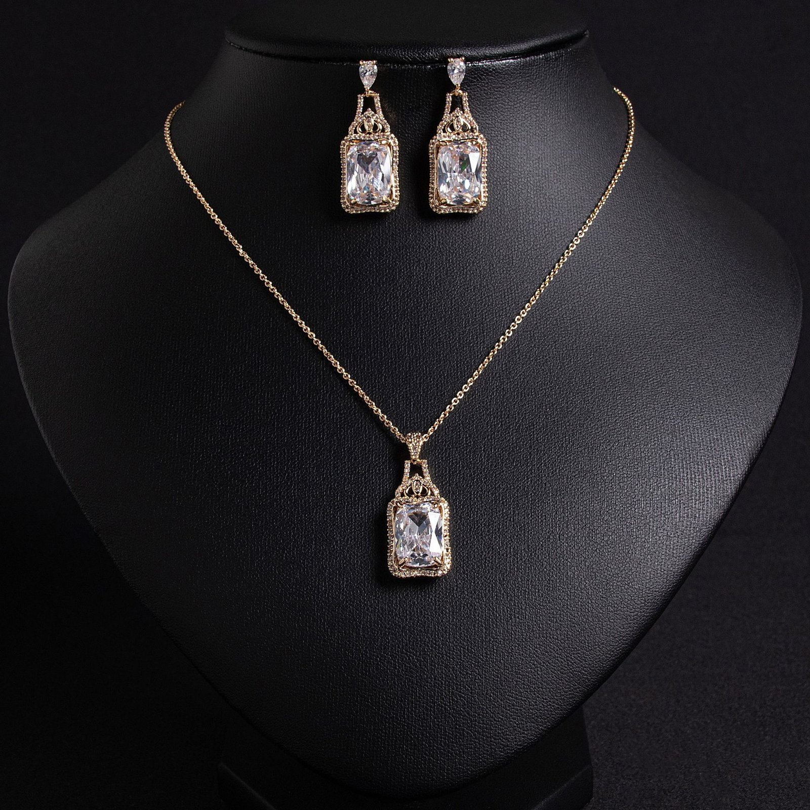 LJT6057 (1) Niche emerald cut zircon halo jewelry set wholesale featuring a rectangular emerald-cut main gem inside an intricate pave cubic zirconia filigree frame with matching drop earrings from junejewelry.com