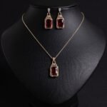Niche emerald cut zircon halo jewelry set wholesale featuring a rectangular emerald-cut main gem inside an intricate pave cubic zirconia filigree frame with matching drop earrings from junejewelry.com