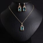 Niche emerald cut zircon halo jewelry set wholesale featuring a rectangular emerald-cut main gem inside an intricate pave cubic zirconia filigree frame with matching drop earrings from junejewelry.com