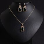 Niche emerald cut zircon halo jewelry set wholesale featuring a rectangular emerald-cut main gem inside an intricate pave cubic zirconia filigree frame with matching drop earrings from junejewelry.com
