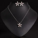 Niche five petal flower jewelry set wholesale featuring a delicate micro-pave CZ five petal blossom pendant necklace and matching flower stud earrings from junejewelry.com