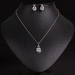 Niche crown zircon halo pendant necklace earring set wholesale featuring a micro-pave crown bail suspending a halo-set round crystal pendant with matching stud earrings from junejewelry.com