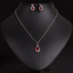 Niche crown zircon halo pendant necklace earring set wholesale featuring a micro-pave crown bail suspending a halo-set round crystal pendant with matching stud earrings from junejewelry.com