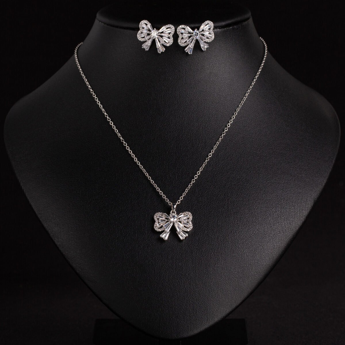 Niche bowknot crystal jewelry set wholesale featuring a sparkly baguette cubic zirconia ribbon bow pendant chain necklace and matching stud earrings from junejewelry.com