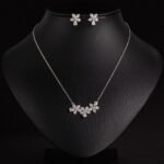 Niche triple flower crystal jewelry set wholesale featuring a curved garland of pave CZ flowers with teardrop crystal accents and matching floral stud earrings from junejewelry.com