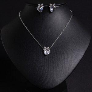 Niche bow heart crystal jewelry set wholesale featuring a delicate pave CZ bow ribbon knot topped heart crystal pendant chain necklace and matching stud earrings from junejewelry.com