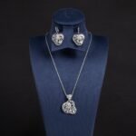 Niche swirl heart crystal jewelry set wholesale featuring an openwork filigree swirl heart pendant necklace studded with cubic zirconia and matching drop earrings from junejewelry.com