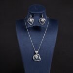 Niche swirl heart crystal jewelry set wholesale featuring an openwork filigree swirl heart pendant necklace studded with cubic zirconia and matching drop earrings from junejewelry.com