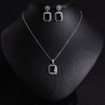 Niche emerald cut crystal jewelry set wholesale featuring a radiant halo CZ rectangular crystal pendant chain necklace and matching drop earrings from junejewelry.com