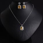 Niche emerald cut crystal jewelry set wholesale featuring a radiant halo CZ rectangular crystal pendant chain necklace and matching drop earrings from junejewelry.com