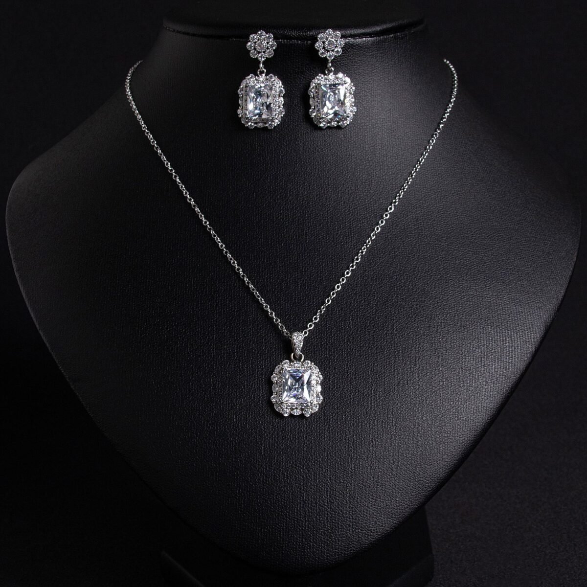 Niche emerald cut crystal jewelry set wholesale featuring a radiant halo CZ rectangular crystal pendant chain necklace and matching drop earrings from junejewelry.com