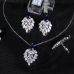 Niche feather crystal cluster jewelry set wholesale featuring marquise CZ leaf cluster pendants topped with pear-cut colored gemstones with matching earrings and ring from junejewelry.com