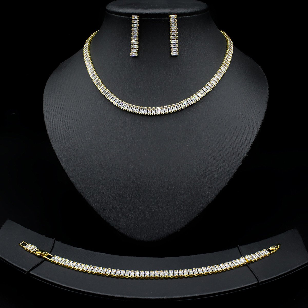 Baguette CZ tennis jewelry set wholesale including necklace, drop earrings, and tennis bracelet featuring emerald-cut cubic zirconia on 18K gold and palladium plated copper.